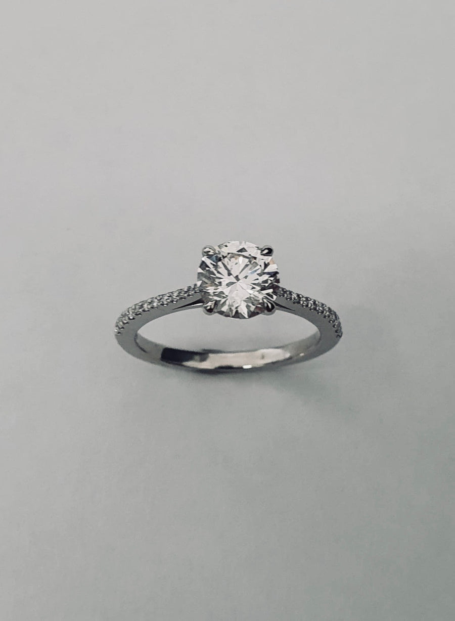 An elegant Platinum Solitaire Engagement Ring see with a Round Brilliant Cut Diamond and Diamond set shoulders