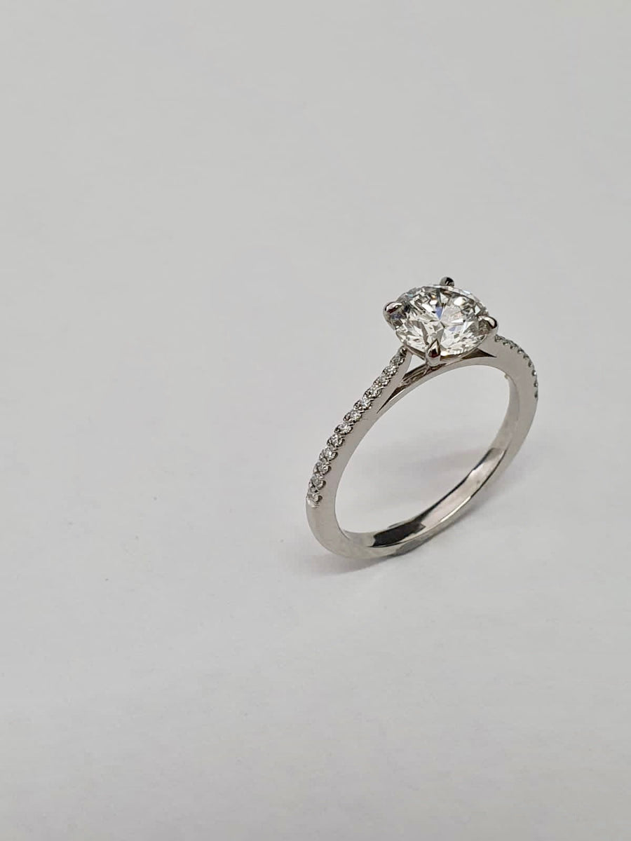 An elegant Platinum Solitaire Engagement Ring see with a Round Brilliant Cut Diamond and Diamond set shoulders