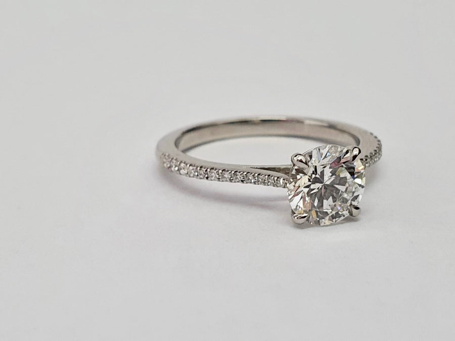 An elegant Platinum Solitaire Engagement Ring see with a Round Brilliant Cut Diamond and Diamond set shoulders