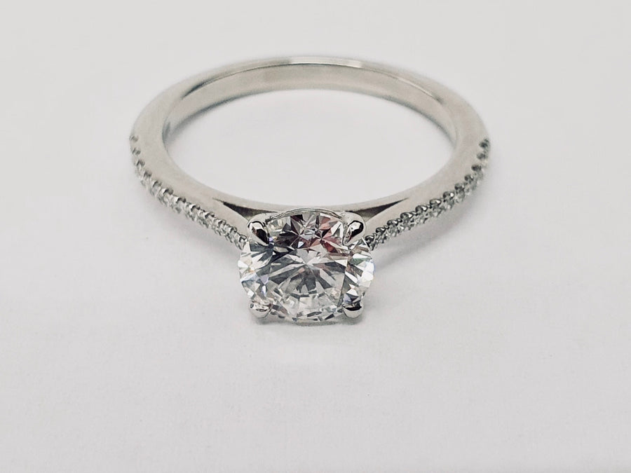 An elegant Platinum Solitaire Engagement Ring see with a Round Brilliant Cut Diamond and Diamond set shoulders