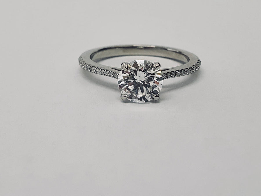An elegant Platinum Solitaire Engagement Ring see with a Round Brilliant Cut Diamond and Diamond set shoulders